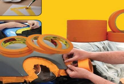 Kỹ thuật viên sử dụng băng keo giấy 3M 244 màu vàng và cam để dán che chắn các chi tiết xe hơi, tạo đường sơn sắc nét.